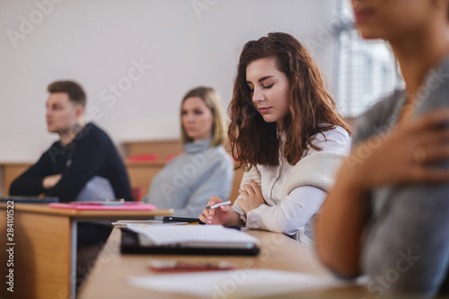 Beautiful girl taking notes in multinational group of students in an auditorium