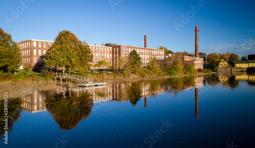 A 19th century textile mill has been renovated for modern use, seen reflected in the neighboring river in Exeter, New Hampshire