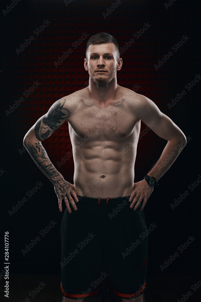 Tattoo strong boxer stand in front of dark background