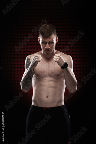 Tattoo strong boxer stand in front of dark background