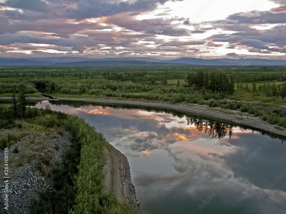 River landscape. Northern reindeer in summer forest. The sky, gr