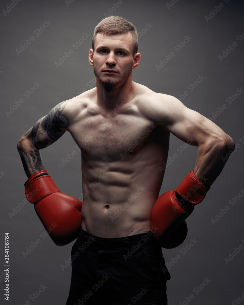 Tattoo strong boxer stand in front of dark background