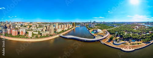 NUR-SULTAN, KAZAKHSTAN - July 30, 2019: Beautiful panoramic aerial drone view to Ishim River Embankment and Nursultan (Astana) city center with skyscrapers and modern pedestrian bridge