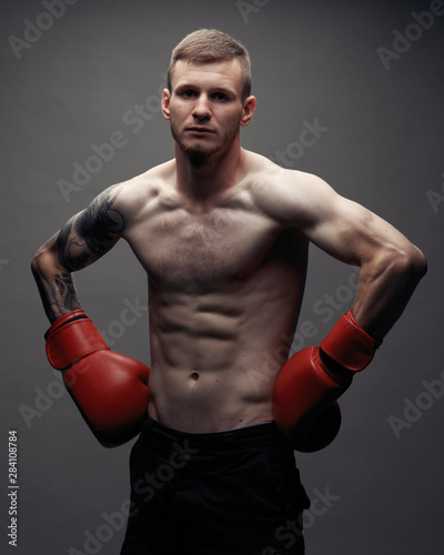 Tattoo strong boxer stand in front of dark background © Rabi
