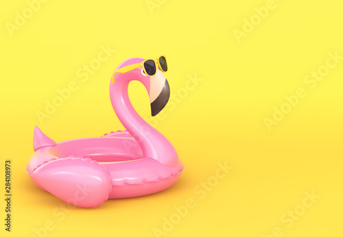 Inflatable flamingo in sunglasses on yellow background