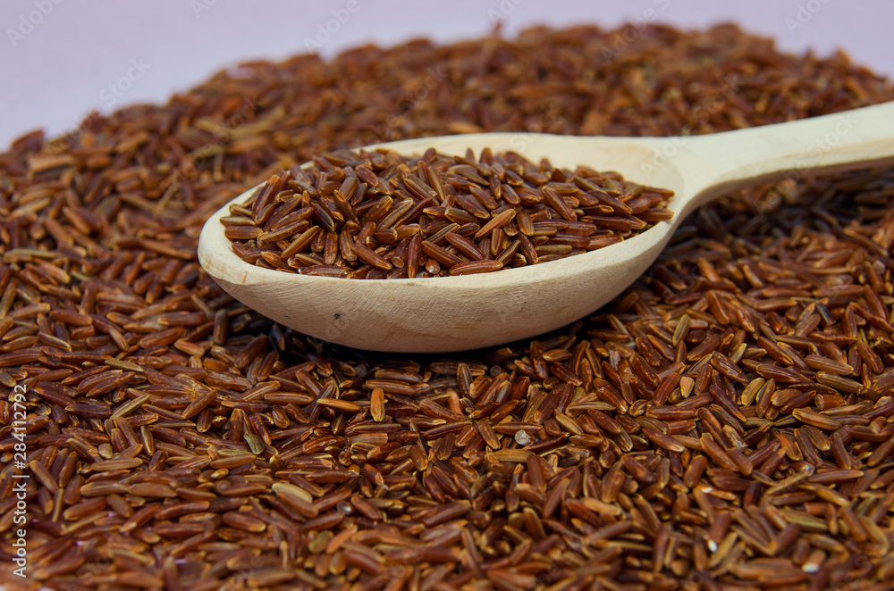 Unpolished red rice in wooden spoon. Long grain red rice, rice background. Red rice. Unpolished red rice in wooden spoon. Long grain red rice, rice background. Red rice.