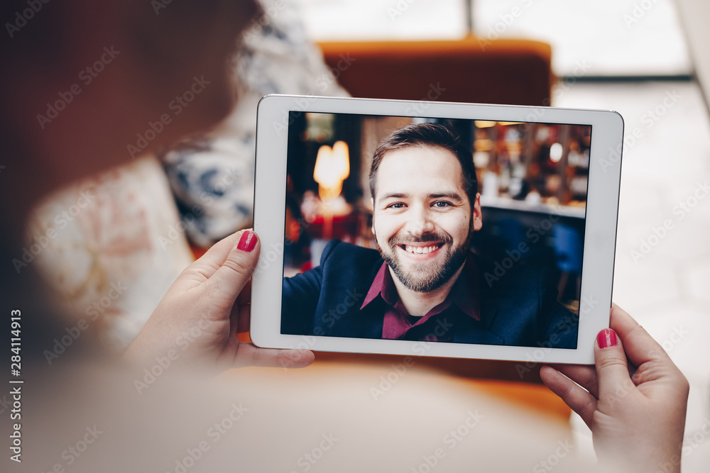 Young woman using a tablet by having a video call chat with her businessman boyfriend who is away on a business trip. Concept of keeping a long distant relationship in a career oriented world.