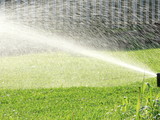 Sprinklers automatic watering grass on a hot summer day. Savings of water from sprinkler irrigation system with adjustable head. Automatic equipment for irrigation and maintenance of lawns, gardening.