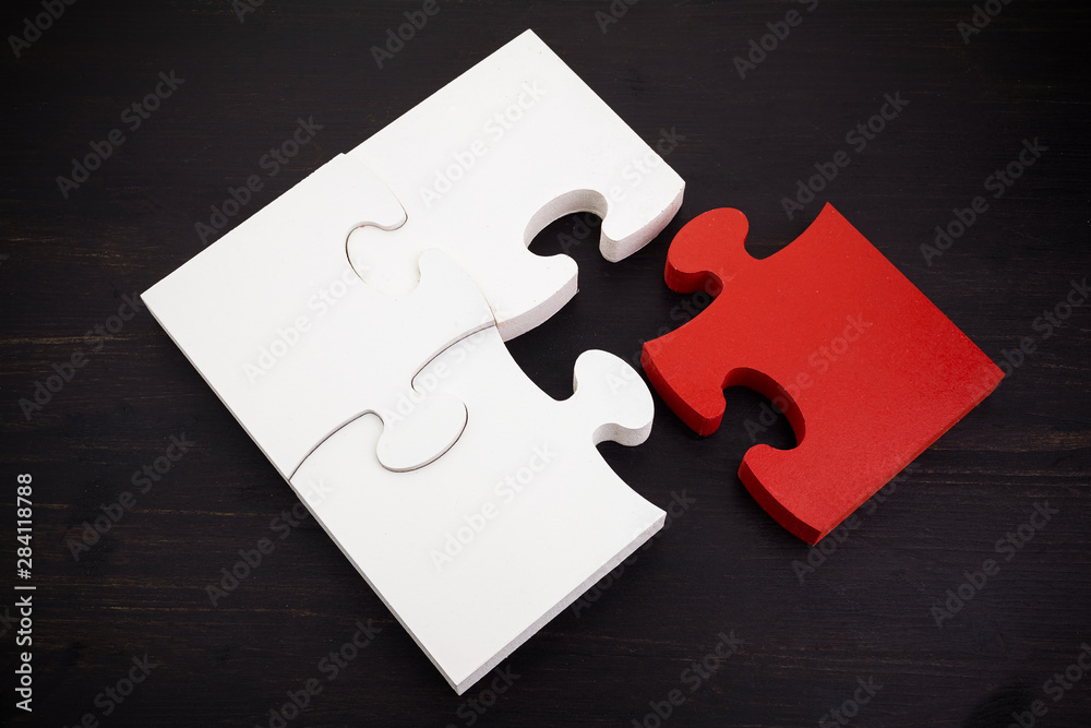 Three onnected jigsaw puzzle pieces and one red on dark wooden background. Finding the right solutions in teamwork. Three onnected jigsaw puzzle pieces and one red on dark wooden background. Finding the right solutions in teamwork.