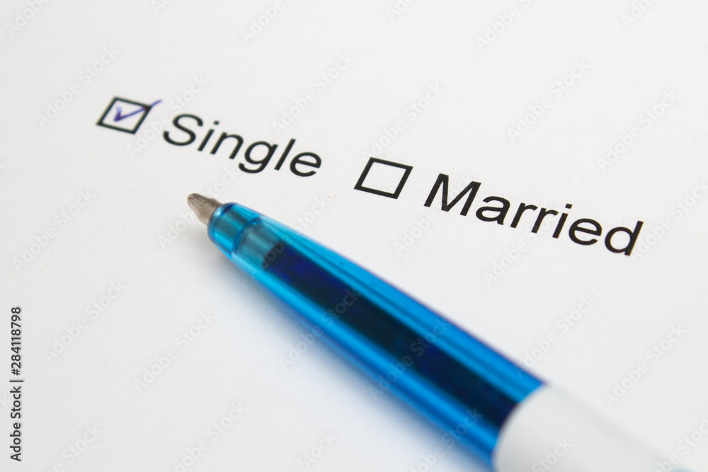 Single or married - checkmark on white paper with pen. Single or married - checkmark on white paper with pen.