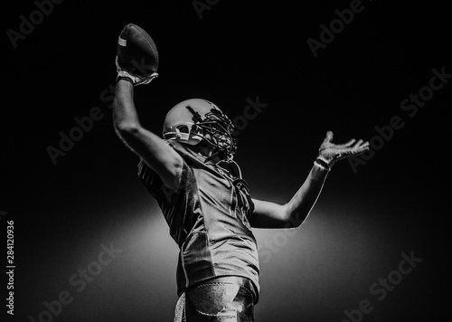 Side view of a teenage boy wearing a sports helmet and jersey holding a ball in his hand during an American football game, California, USA
