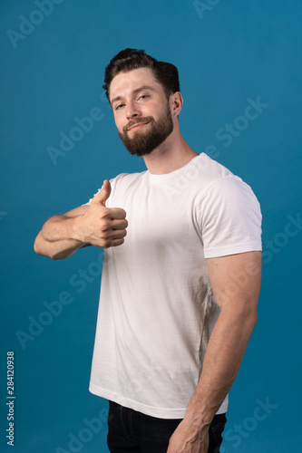 happiness, gesture and people concept - smiling man showing thumbs up. Portrait of a handsome man. White T-shirt, good muscles.