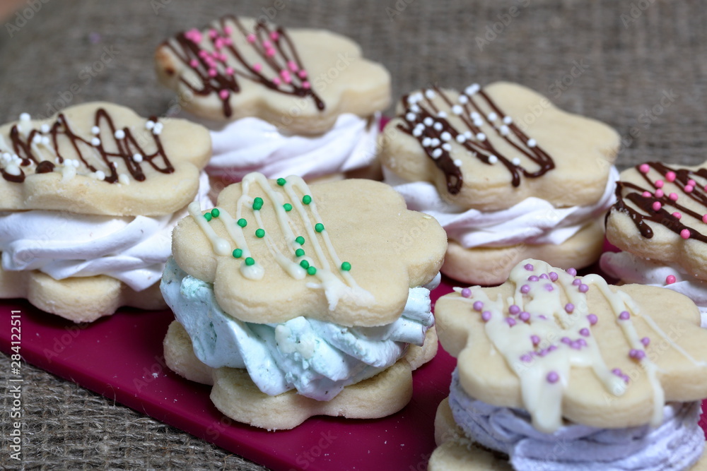 Marshmallow sandwich decorated with chocolate and decorative sprinkles. Set with decoration of different colors. Close-up shot.