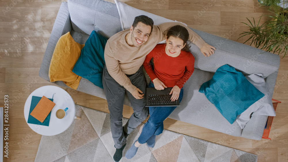 Young Beautiful Couple is Sitting on a Sofa, Using a Laptop. They Look ...