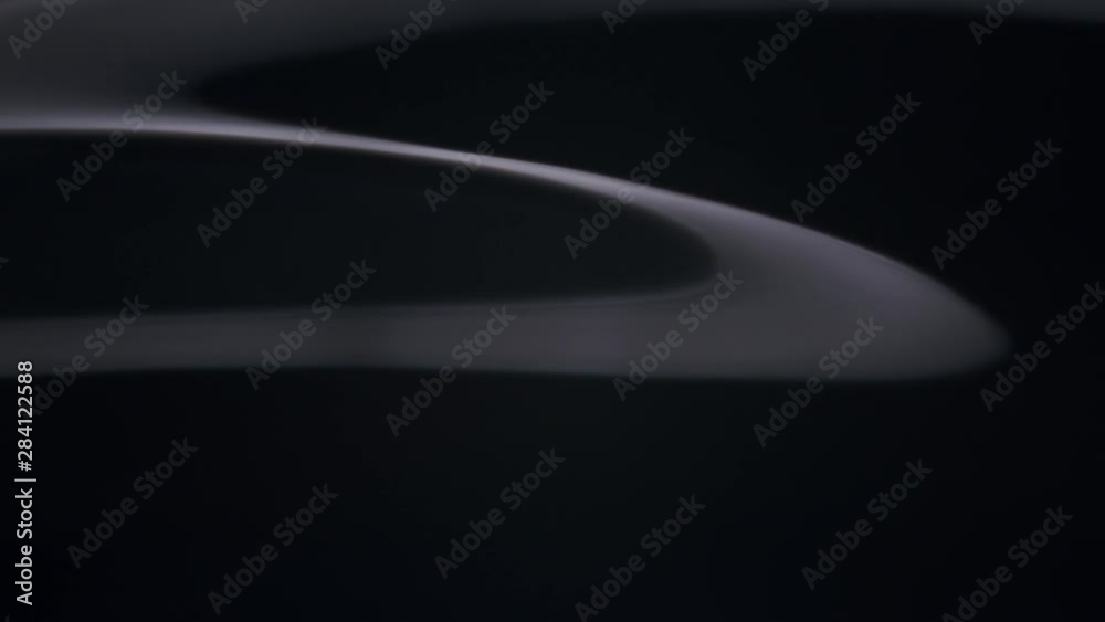 three dimensional white ribbon in a black surrounding. small white blush in a black orbit/ space/universe. a white shine in the darkness. detail of an edge reflecting in total darkness