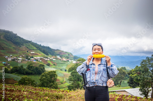 Fat Asian female tourist eating corn during traveling at Mon Cham, Chiang Mai