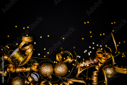 Gllasses of champagne on black stylish background with Place for text. Festive concept.Golden stylish decoration on black background. Sticky tape, Christmas balls, golden ribbon