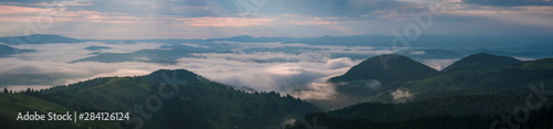 Amazing sunrise in the mountains. Great view of the foggy valley with bright sun rays in Carpathians. Impressive mountain landscape with rising sun and rugged mountains raise above the clouds.