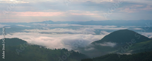 Amazing sunrise in the mountains. Great view of the foggy valley with bright sun rays in Carpathians. Impressive mountain landscape with rising sun and rugged mountains raise above the clouds. © Viktoria