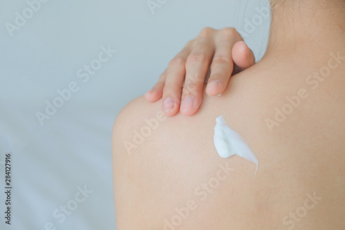 The woman is applying cream,lotion on her back., Hygiene skin body care concept.