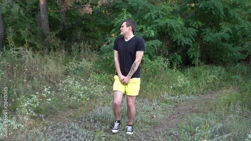 A handsome young man is suffering from the urge to pee in the forest. photo