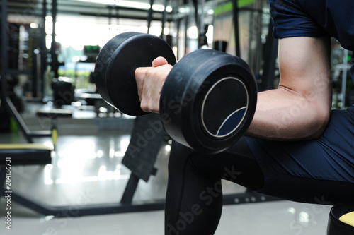 A man raising dumbbell for exercise his biceps looking good, Concentration curls,Healty with exercise in the gym,Seletive focus