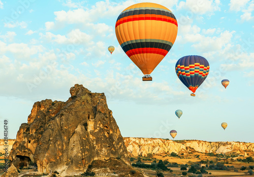 Colorful air balloons fly up into the sky at sunrise among a beautiful rocky landscape. Cappadocia Turkey.