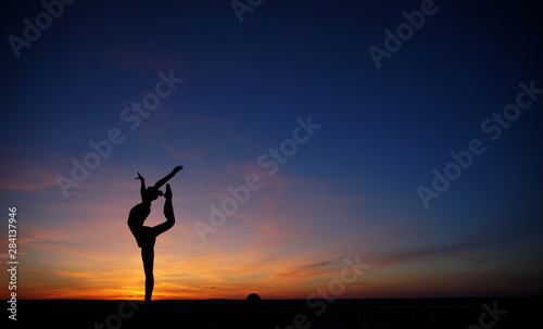 dancer in the dance does the splits in the air against the sunset. © Oleksandr