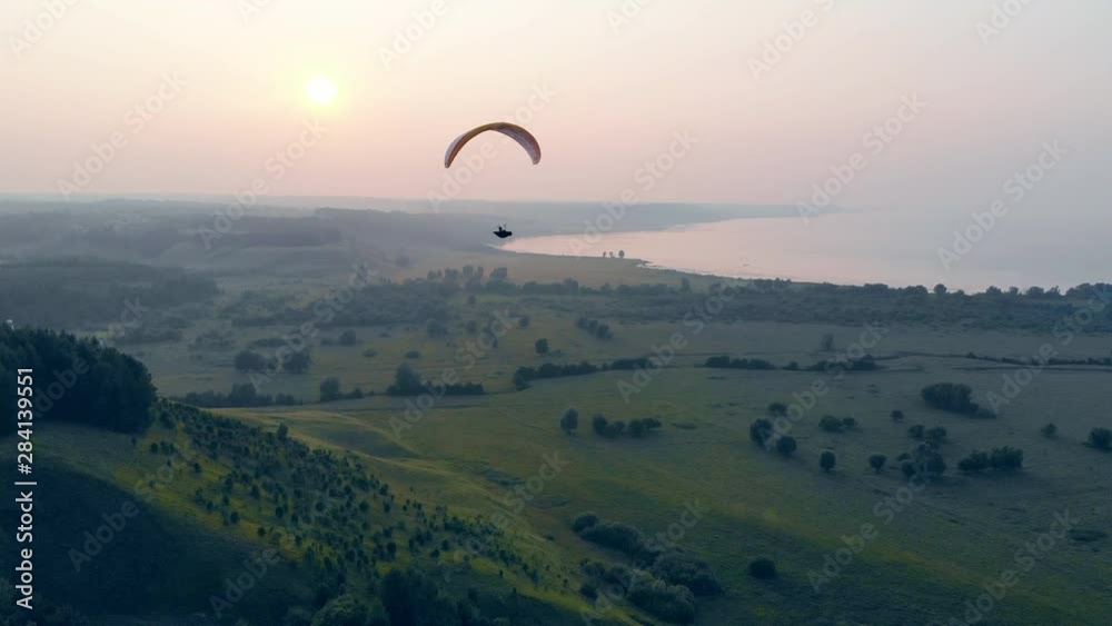 Green foggy scenery with a parafoil drifting along it. Parachute, paragliding comcept. Green foggy scenery with a parafoil drifting along it. Parachute, paragliding comcept.
