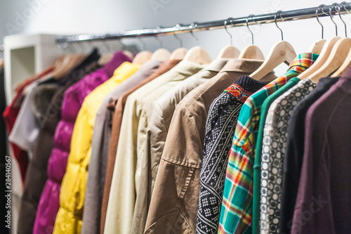 Colorful selection of clothes for men and women hanging on hangers in a mall for a store sale concept.