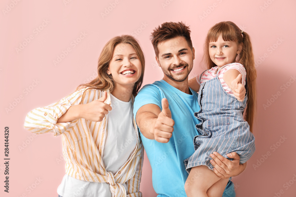 Portrait of happy family showing thumb-up gesture on color background
