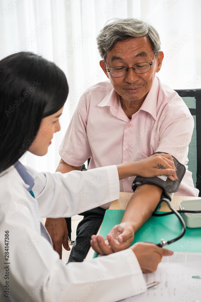 Obraz premium Doctor measuring blood pressure of elderly man in medical office.