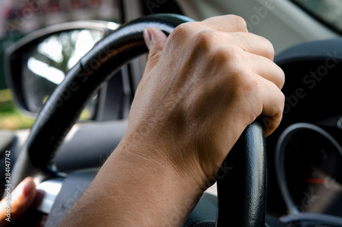 Close up shot of a man's hands holding a car's steering wheel. auto