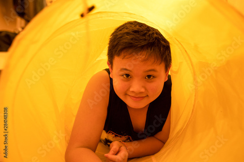 Asian young boy with smile face playing in yellow tent tunnel