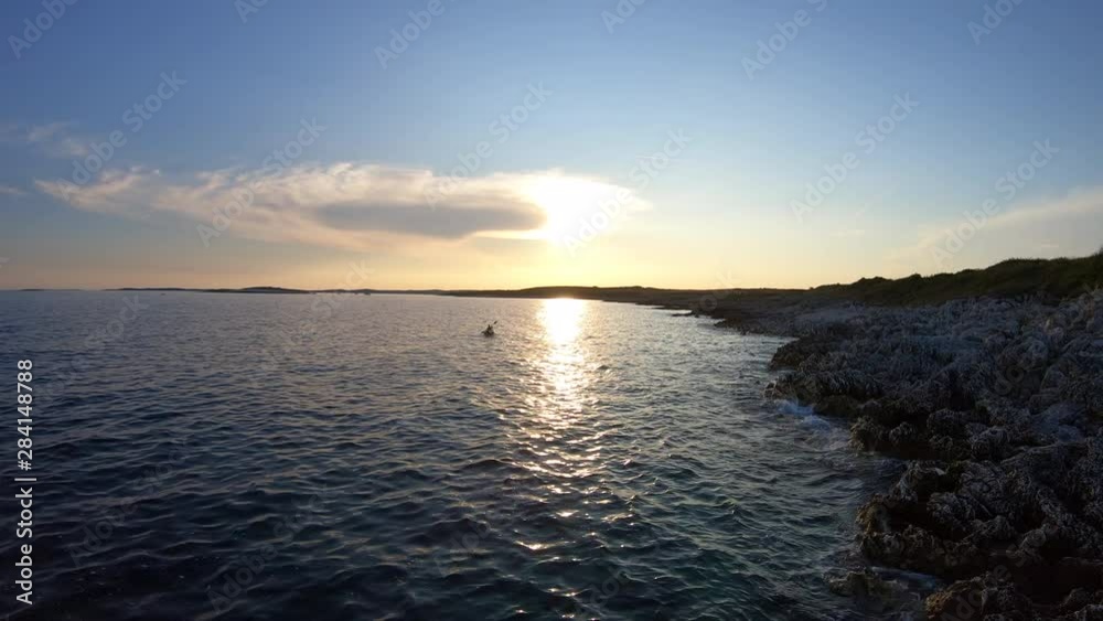 AERIAL: Kayaker at sea in setting sun AERIAL: Kayaker at sea in setting sun