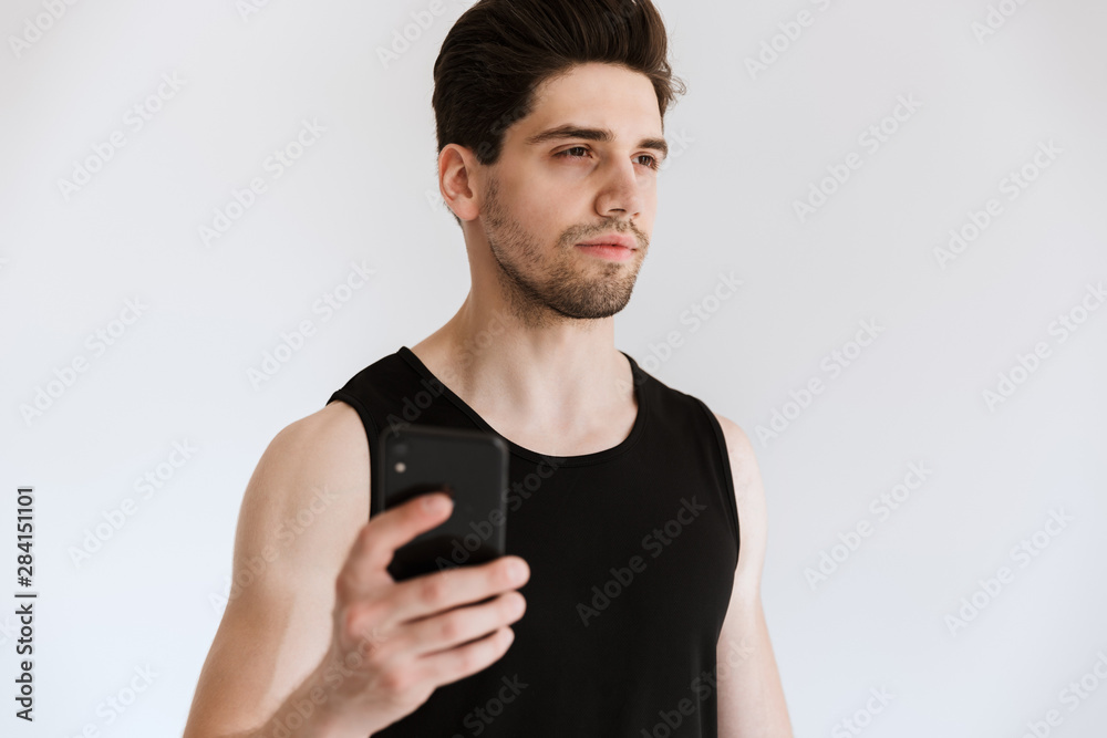 Handsome confident sportsman holding mobile phone Handsome confident sportsman holding mobile phone