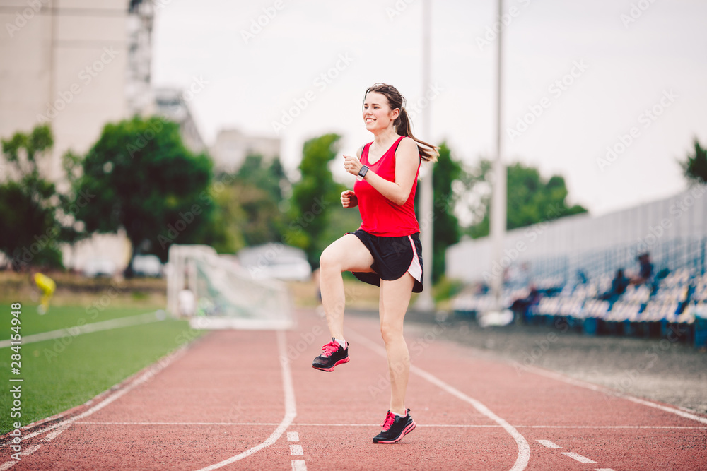 Female athlete preparing legs for cardio workout. Fitness runner doing warm-up routine. woman runner warm up outdoor. athlete stretching and warming up on a running track in a stadium