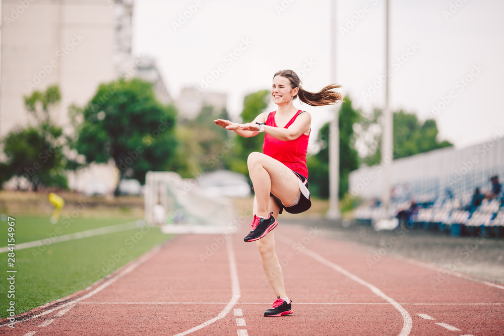 Female athlete preparing legs for cardio workout. Fitness runner doing warm-up routine. woman runner warm up outdoor. athlete stretching and warming up on a running track in a stadium