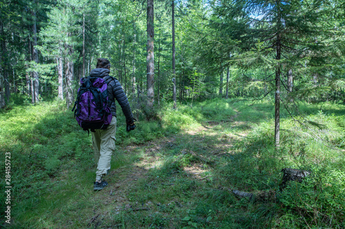 A man with a large tourist backpack traveling through the woods  ecotourism concept.