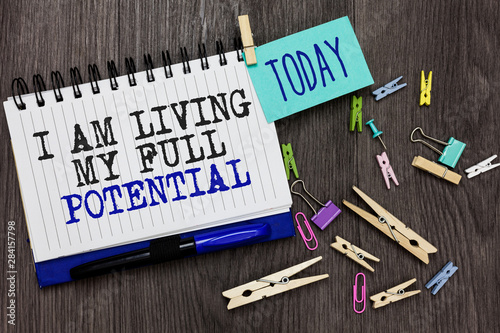 Writing note showing I Am Living My Full Potential. Business photo showcasing Embracing opportunities using skills abilities Different paperclip on woody table pinch on written notepad blue pen photo