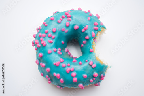 Bitten blue donut with bright sprinkles on a isolated background, food concept