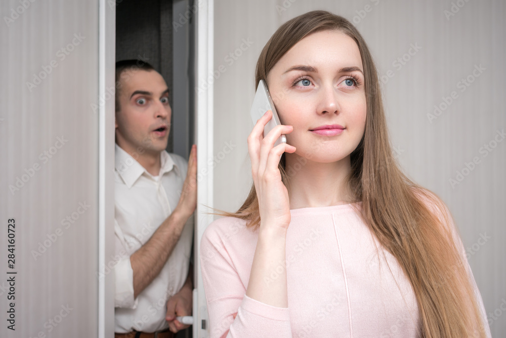 Nosey guy peeps into the phone girl, beautiful girl uses a smartphone, portrait, close up