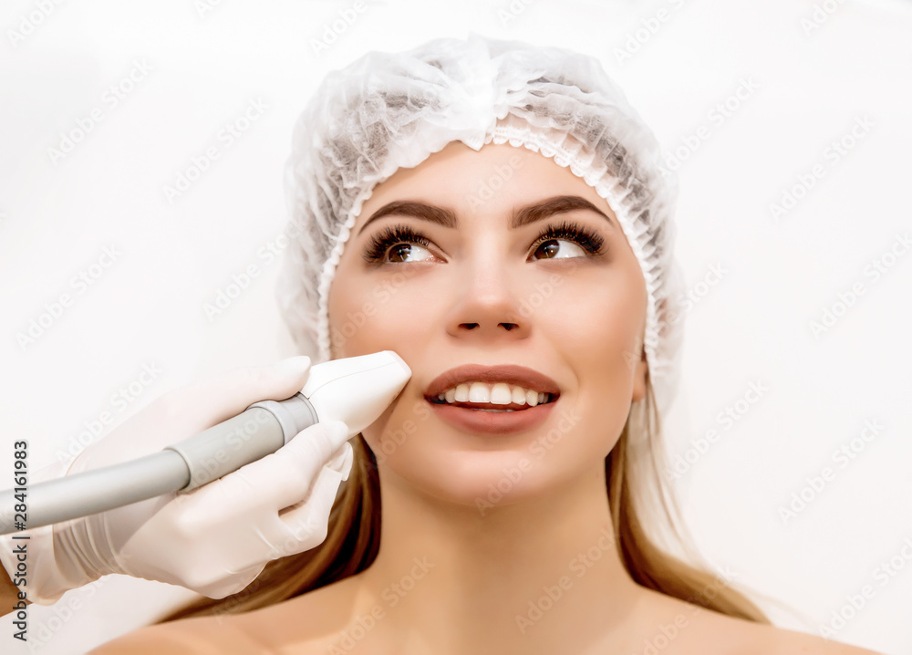 Young beautiful woman on cosmetic procedure in beauty center. Medical centre. Hardware cosmetology. Face lift and wrinkle correction Young beautiful woman on cosmetic procedure in beauty center. Medical centre. Hardware cosmetology. Face lift and wrinkle correction