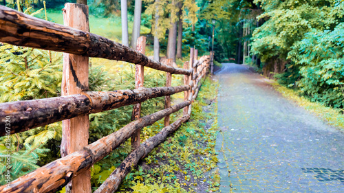 Wooden fence and country road in the mountains. Summer day