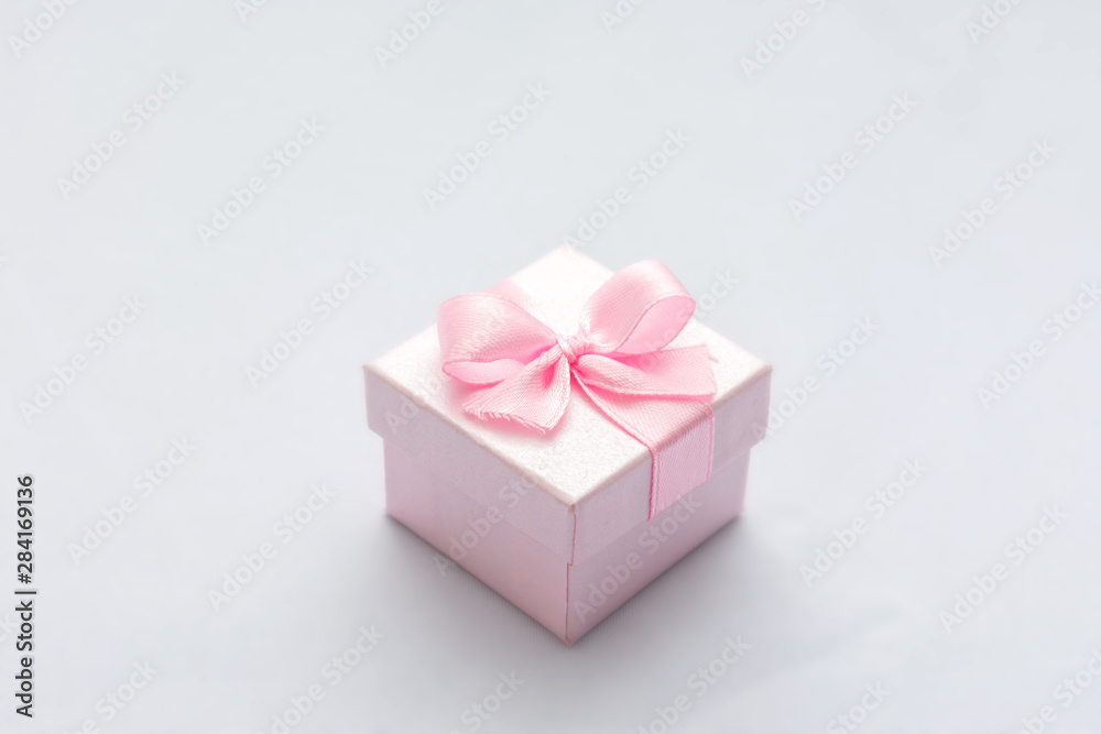 Pink square gift box, blue background, copy space, for text, close up Pink square gift box, blue background, copy space, for text, close up