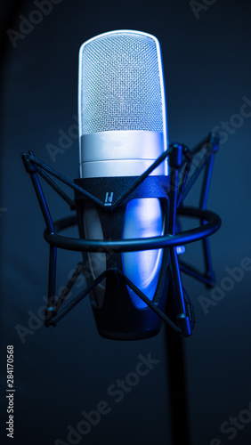 silver studio condenser microphone, isolated on gradient. with blue light 