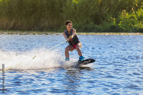 Happy girl riding on wakeboard at sunny day , smiling and happy 