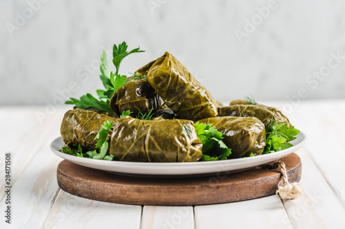 Delicious stuffed grape leaves (traditional doom Mediterranean cuisine Dolma) on a black plate with fresh cilantro and dill
