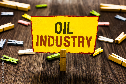 Handwriting text writing Oil Industry. Concept meaning Exploration Extraction Refining Marketing petroleum products Clothespin holding yellow paper note several clothespins wooden floor