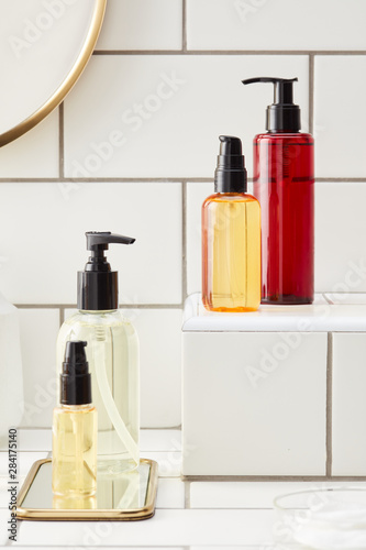 Colorful cosmetic bottles composed on white tiles photo